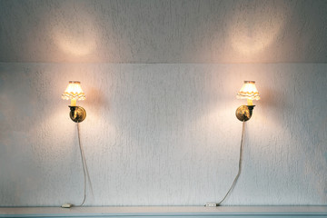 Two vintage lamps on the wallpaper . Wall light of gilded metal with two electric candles