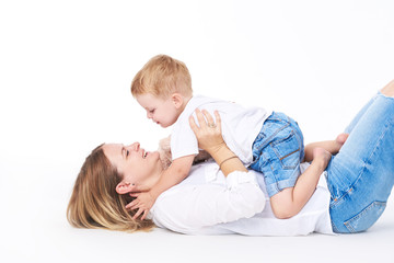 Happy young mother having fun with her toddler child - Son hugging his mum on white background - Family lifestyle, motherhood, love and tender moments concept