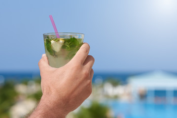 Man's hand with mojito against wonderful seaview.