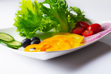 Fresh mixed vegetables salad with black olives on white plate. Close up. Selective focus.