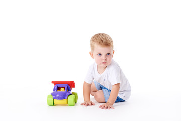 Fototapeta premium Cute boy plaing with toy car on floor, isolated on white