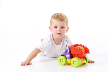 Cute boy plaing with toy car on floor, isolated on white