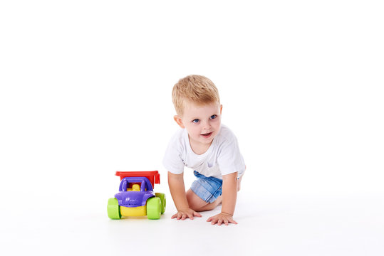 Cute boy plaing with toy car on floor, isolated on white