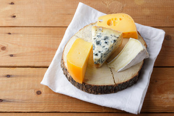 Cheese on white cloth. Camembert, hard yellow cheese, dorblu on wooden boards. Milk products on white napkin
