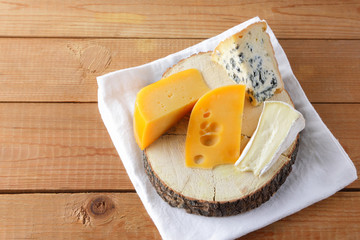 Cheese on white cloth. Camembert, hard yellow cheese, dorblu on wooden boards. Milk products on white napkin