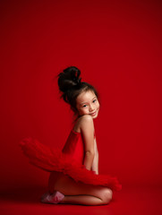 Cute little girl ballerina ballet dancer in beautiful dress is dancing on red 