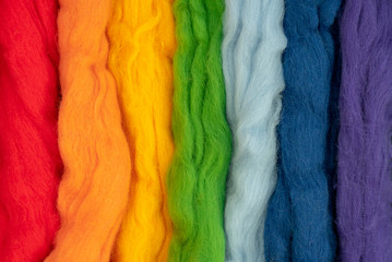 Tufts of wool of different colors parallel to each other form a rainbow. Conceptual photo