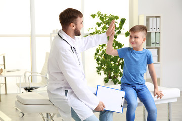 Children's doctor giving high five to patient in hospital