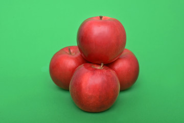 Four red apples on the green background