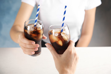 Friends with glasses of tasty refreshing cola at table, closeup view