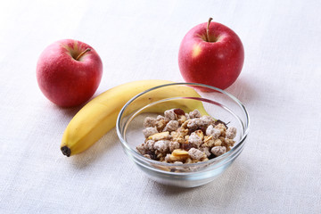 Healthy breakfast with banana, apple and Fresh granola, muesli in bowl on textile background. Top view.