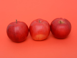 three red apples on the red background