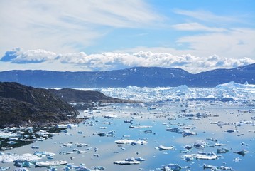 Fototapeta na wymiar Ilulissat, Greenland, July | UNESCO world heritage site | impressions of Jakobshavn | Disko Bay Kangia Icefjord | huge icebergs in the blue sea on a sunny day | climate change - global warming