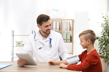 Doctor checking little boy's pulse with medical device in hospital