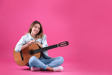 Young woman with acoustic guitar on color background. Space for text