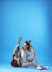 Obraz na płótnie Canvas Young woman with electric guitar on color background