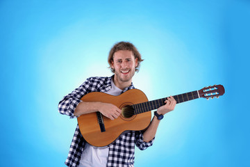 Obraz premium Young man playing acoustic guitar on color background