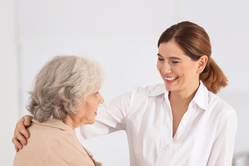 Elderly woman with nurse on light background