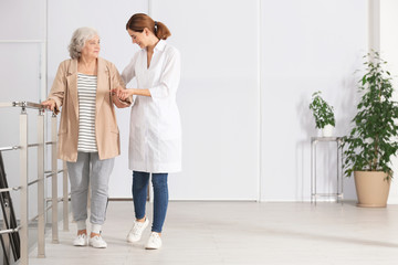 Elderly woman with caregiver indoors. Space for text