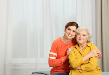 Elderly woman with female caregiver at home. Space for text