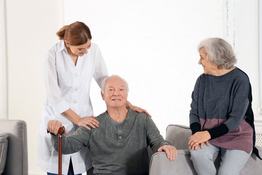 Elderly spouses with female caregiver in living room