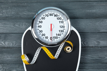 Scales and measuring tape on wooden background, top view. Weight loss