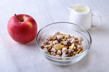 Healthy breakfast. Fresh granola, muesli with coconut, banana apple and nuts with milk in a white bowl on textile background. Top view.