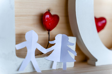 Isolated Origami Paper Boy and Girl Holding Hands With a Red Heart Between Them and the Word "Love" Behind with Wooden Background - Concept of Love, Happiness and Joy, Partly Blurred