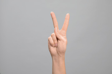 Woman showing number two on grey background, closeup. Sign language