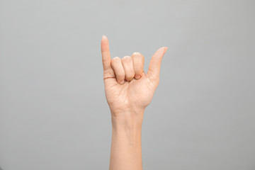 Woman showing Y letter on grey background, closeup. Sign language