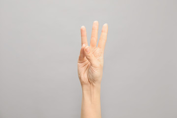 Woman showing number six on grey background, closeup. Sign language