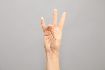 Woman showing number seven on grey background, closeup. Sign language