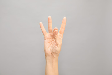 Woman showing number eight on grey background, closeup. Sign language