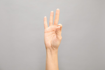 Woman showing number nine on grey background, closeup. Sign language