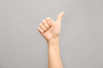 Woman showing number ten on grey background, closeup. Sign language