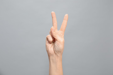 Woman showing number two on grey background, closeup. Sign language
