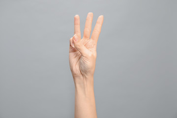 Woman showing number six on grey background, closeup. Sign language