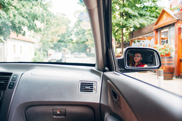 Fototapeta premium Reflection of young girl in wing mirror
