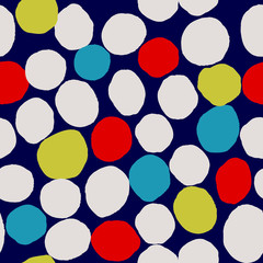 Abstract seamless pattern with irregular dots in blue, yellow, cream and red on dark blue background.