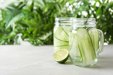 Mason jars of fresh cucumber water on table. Space for text