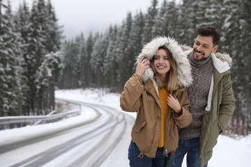 Obraz premium Couple walking near snowy forest, space for text. Winter vacation