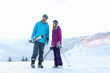 Happy couple with ski equipment spending winter vacation in mountains. Space for text