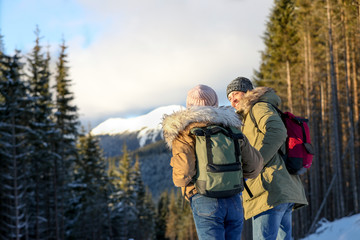 Couple with backpacks enjoying mountain view during winter vacation. Space for text