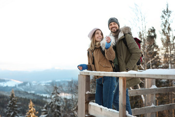Couple spending winter vacation together in mountains. Space for text