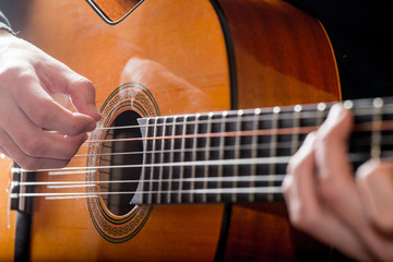Obraz premium adult white guy playing an acoustic guitar. Backlit shooting