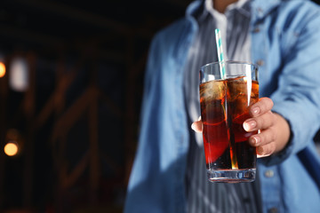 Woman with glass of refreshing cola indoors, closeup. Space for text