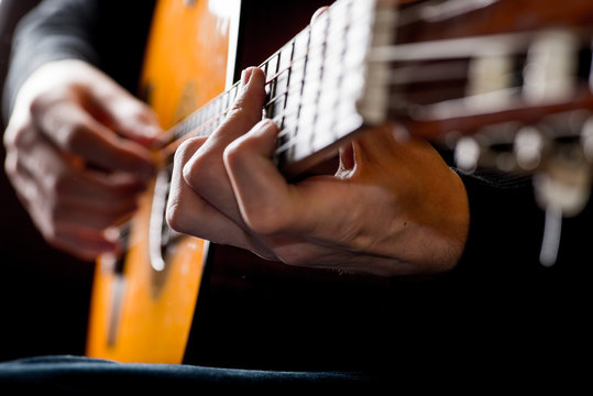 adult white guy playing an acoustic guitar. Backlit shooting