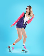 Young woman with retro roller skates on color background