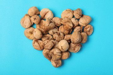 Heart shaped heap of dried figs on color background, top view. Healthy fruit