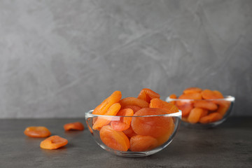 Bowl with dried apricots on grey table, space for text. Healthy fruit